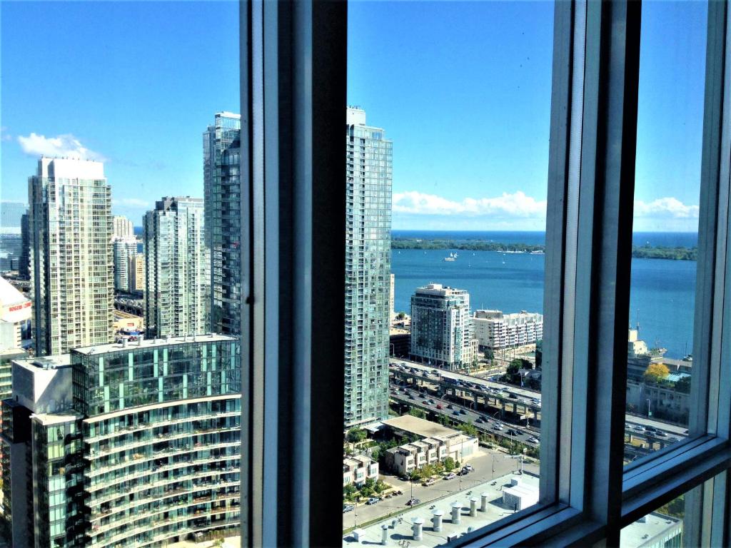 Elle offre une vue sur les toits de la ville depuis sa fenêtre. dans l'établissement TVHR - Luxury Condos in Heart of Downtown, à Toronto
