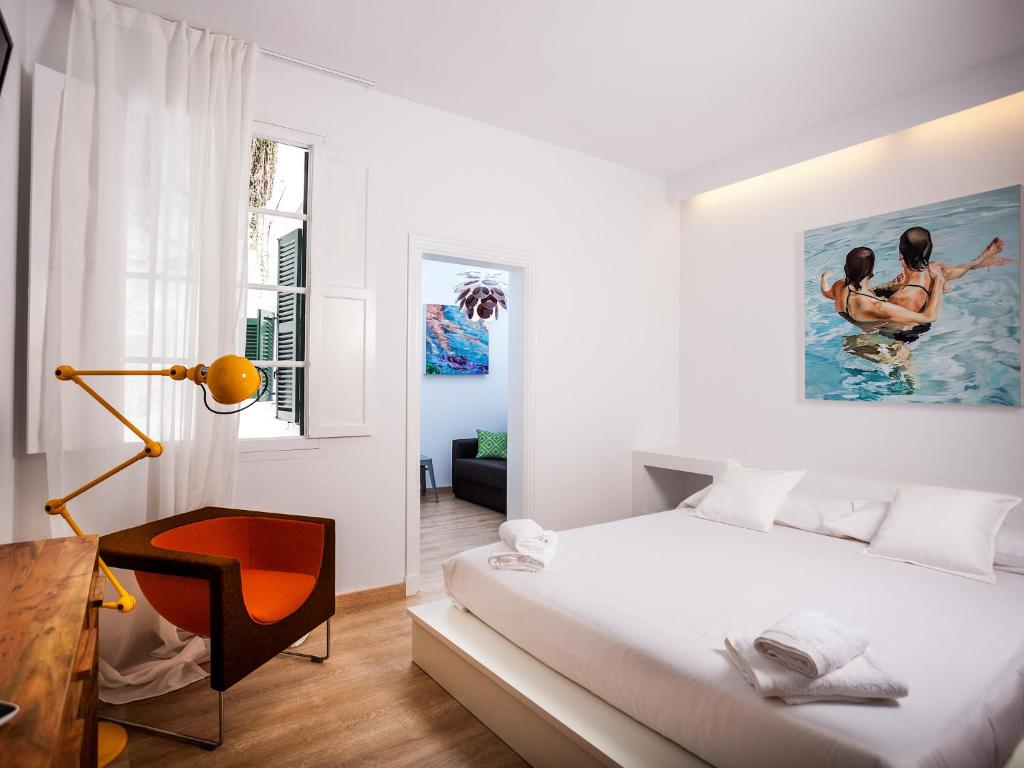 a white bedroom with a bed and a desk at Cheap & Chic Hotel in Ciutadella