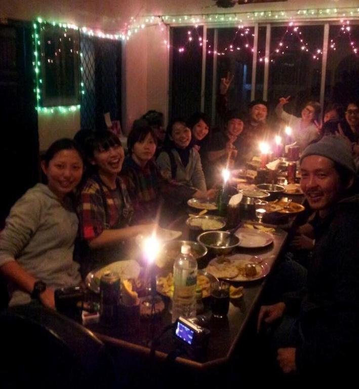 um grupo de pessoas sentadas em torno de uma mesa longa com luzes em Shiva Guest House em Varanasi