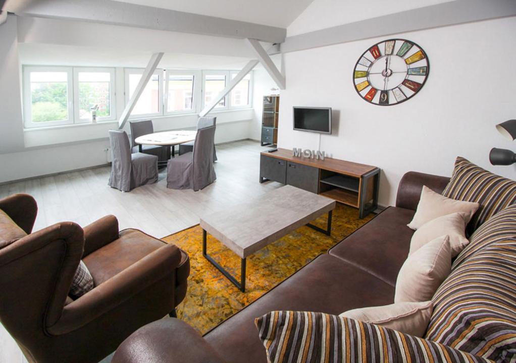 ein Wohnzimmer mit einem Sofa und einer Uhr an der Wand in der Unterkunft Schiller-Quartier 15 in Bremerhaven