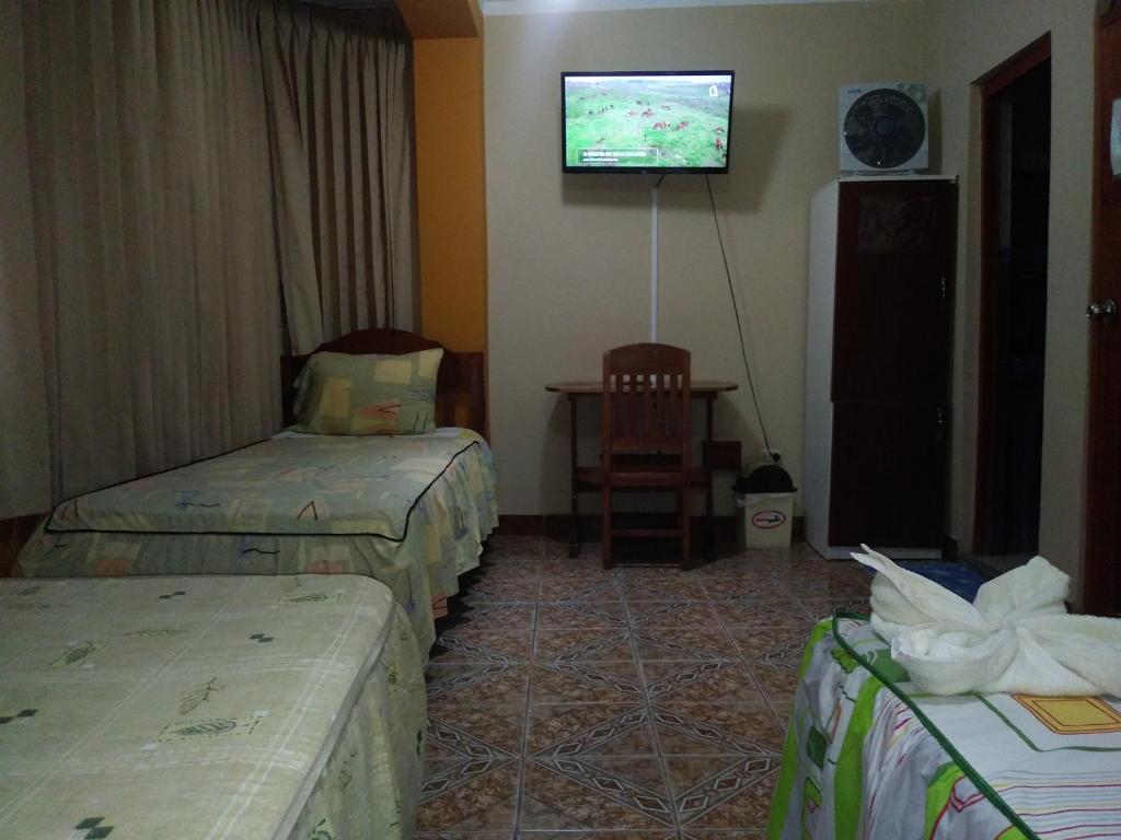 Una habitación con tres camas y un televisor en la pared. en Hospedaje La Terraza, en Jaén