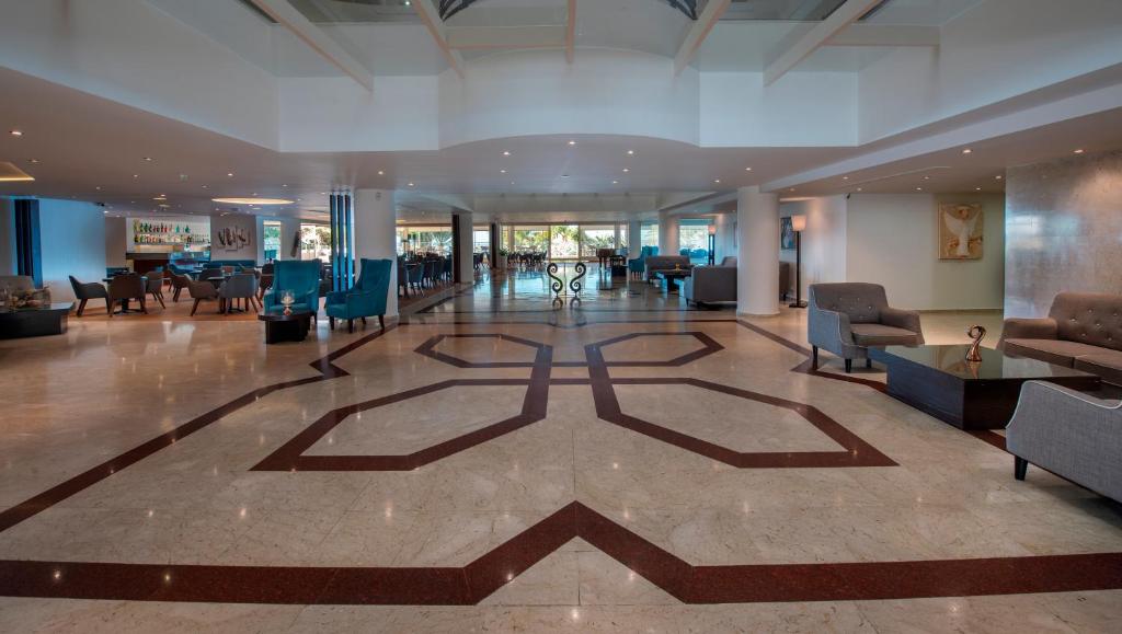 a lobby with chairs and tables in a building at Queens Bay Hotel in Paphos