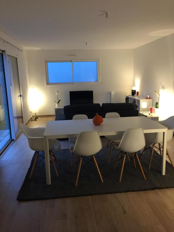 een woonkamer met een witte tafel en stoelen bij Maison Jardin De La Baie in Douarnenez