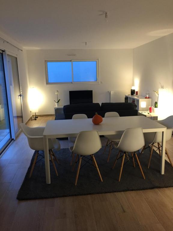 a living room with a white table and chairs at Maison Jardin De La Baie in Douarnenez
