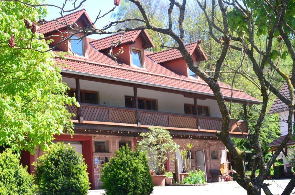 un edificio con techo rojo con árboles y arbustos en Ferienwohnungen Hof Heiderich, en Beerfelden