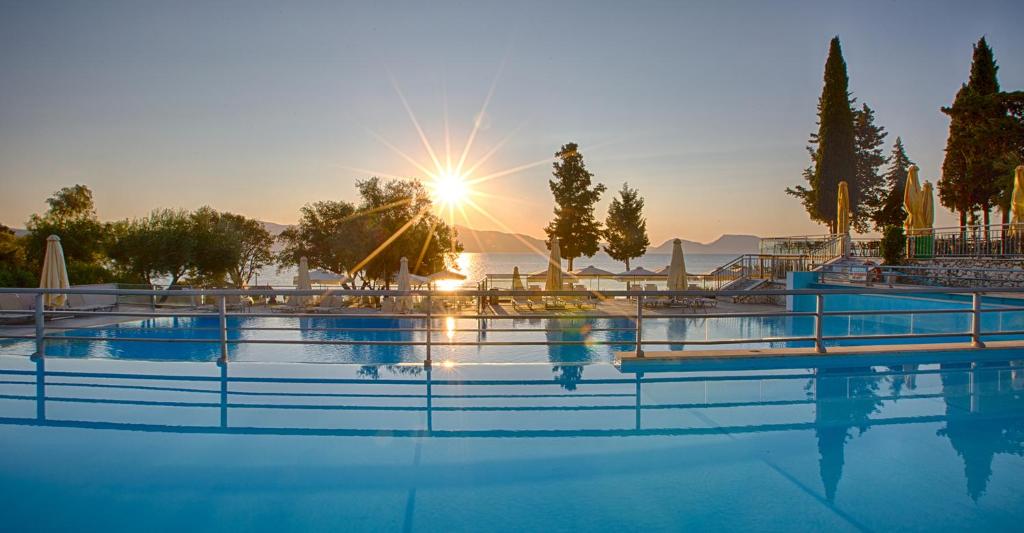 a swimming pool with the sun setting in the background at Porto Galini Seaside Resort & Spa in Nikiana