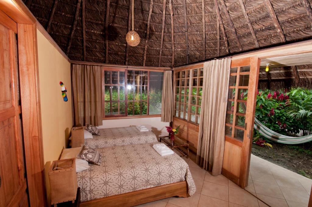 Huasquila Amazon Lodge في Cotundo: غرفة نوم بسرير ونوافذ