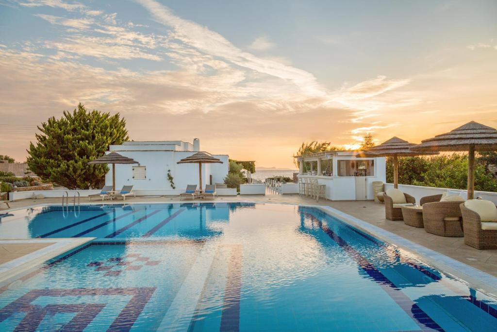 uma piscina com cadeiras e guarda-sóis num edifício em Ostria Inn em Moutsoúna