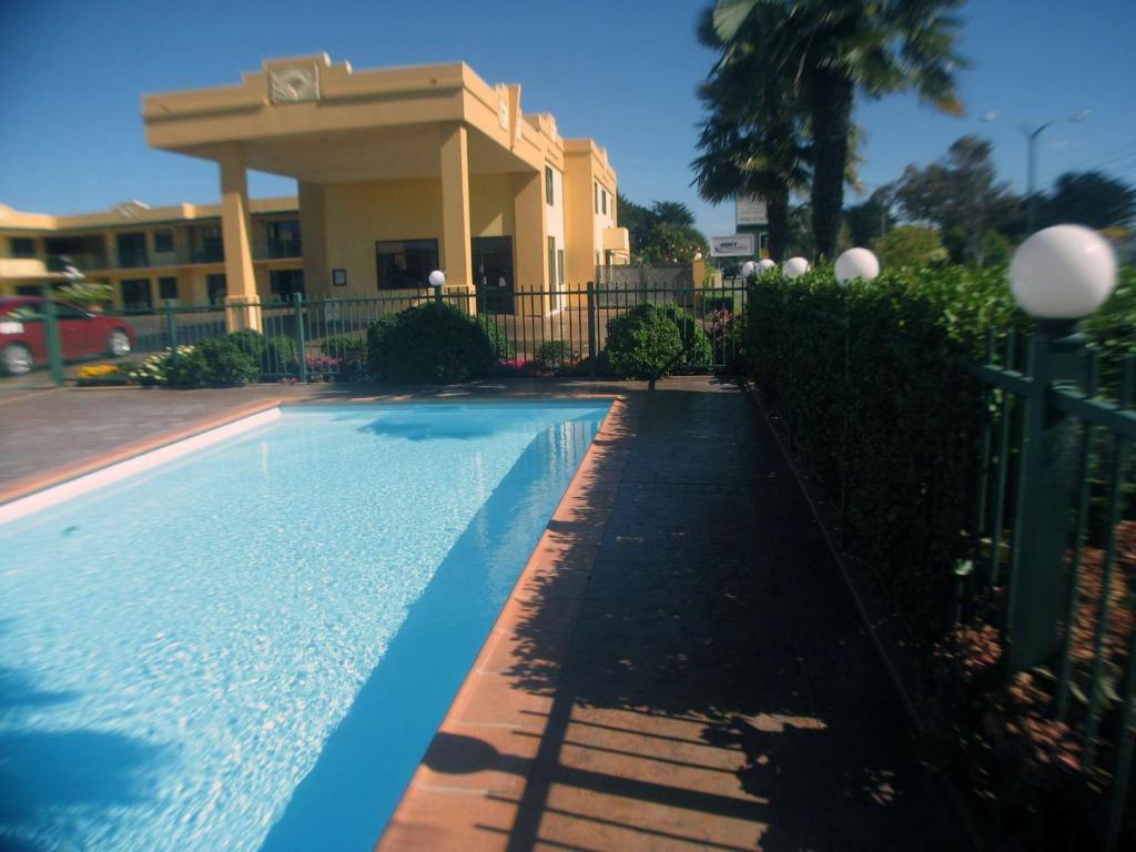 a swimming pool in front of a building at Deco City Motor Lodge in Napier