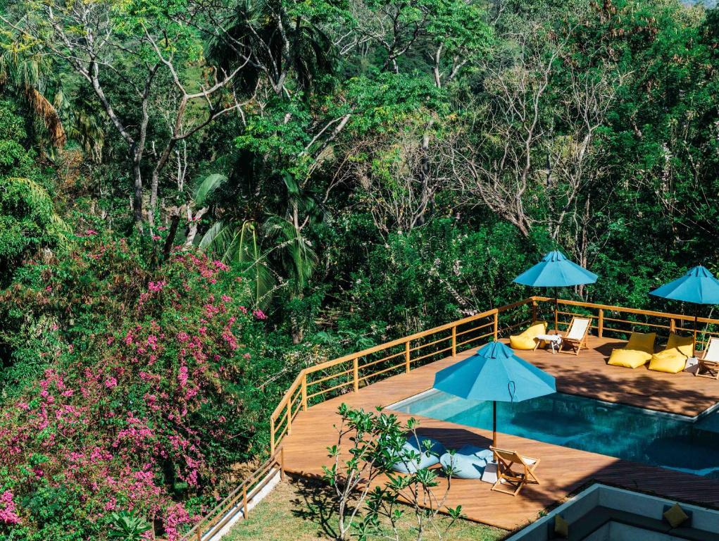 una terraza de madera con sombrillas y una piscina en Rukgala Retreat, en Digana