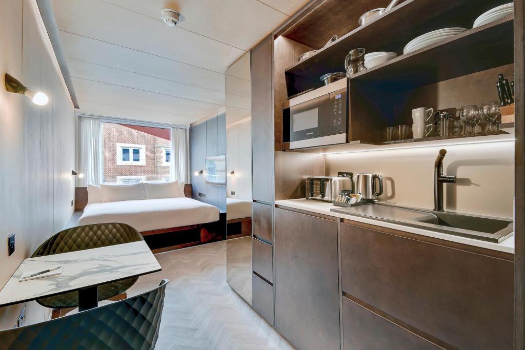 a kitchen with a sink and a room with a bed at StowAway Waterloo in London