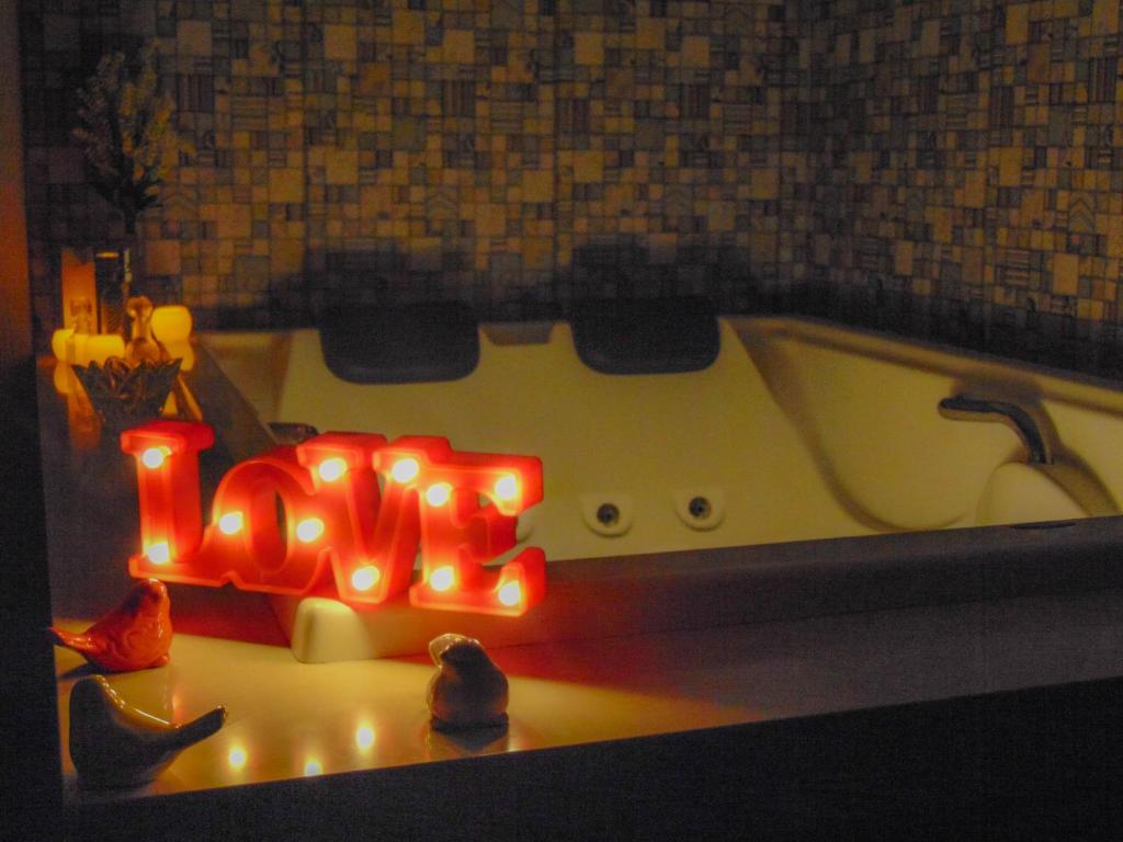 a neon sign sitting in a bath tub at Arraialferias Suites in Arraial do Cabo