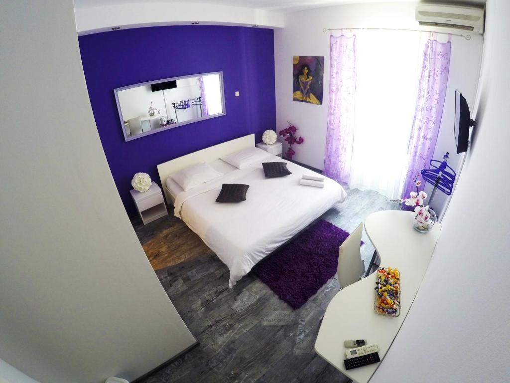 1 dormitorio con cama blanca y pared morada en Rooms and Apartment Stambuk en Split
