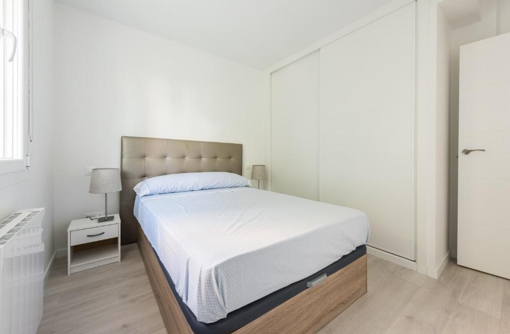 a white bedroom with a bed and a lamp at Apartment IFEMA-Airport in Madrid