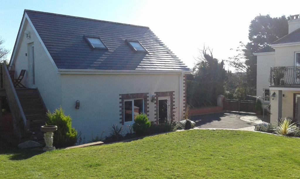 a white house with a black roof and a yard at Garden View Apartment in Salcombe