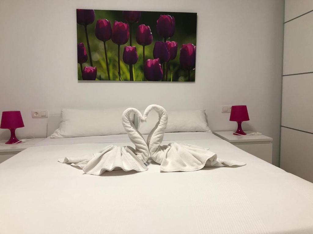 Una cama blanca con dos toallas blancas formando un corazón en Apartamento Centro Historico Teruel, en Teruel