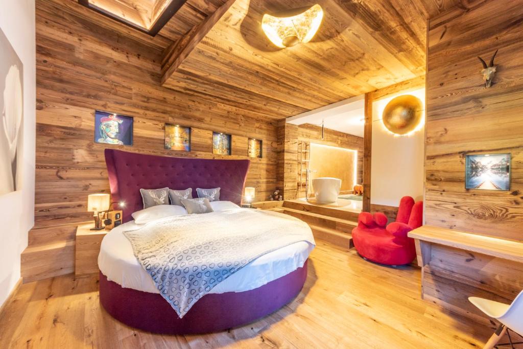1 dormitorio con 1 cama grande en una habitación con paredes de madera en Alpine Residence Villa Adler, en San Vigilio Di Marebbe