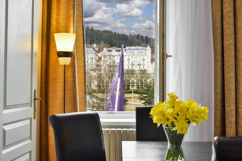 a vase of yellow flowers on a table in front of a window at Apartments Central Park Marienbad in Mariánské Lázně