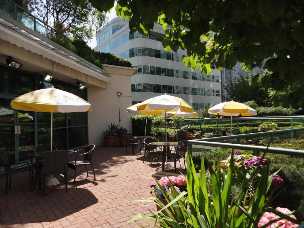 a patio with tables and chairs with umbrellas at Rosedale on Robson Suite Hotel in Vancouver