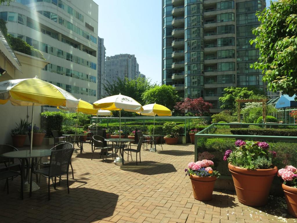 a patio with tables and chairs and umbrellas at Rosedale on Robson Suite Hotel in Vancouver