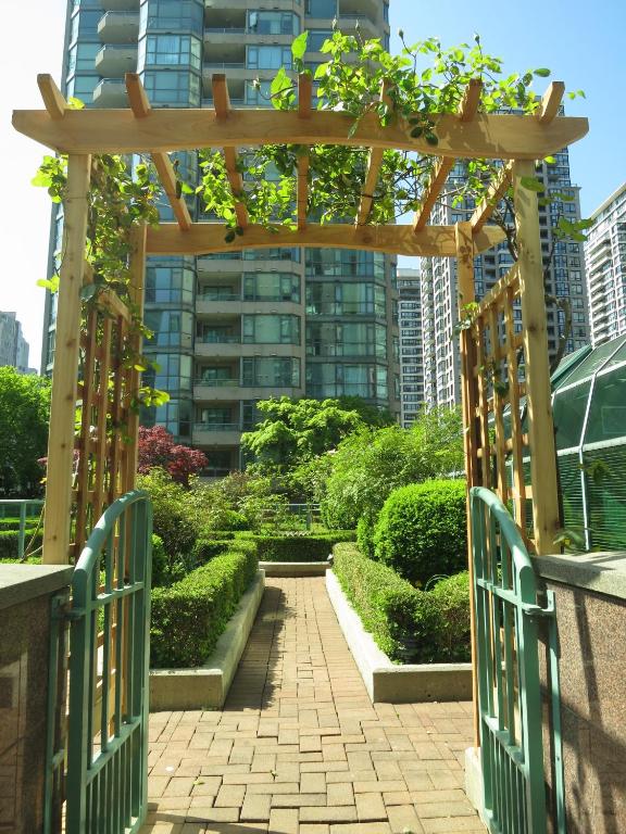 a wooden gate leading to a garden with bushes at Rosedale on Robson Suite Hotel in Vancouver