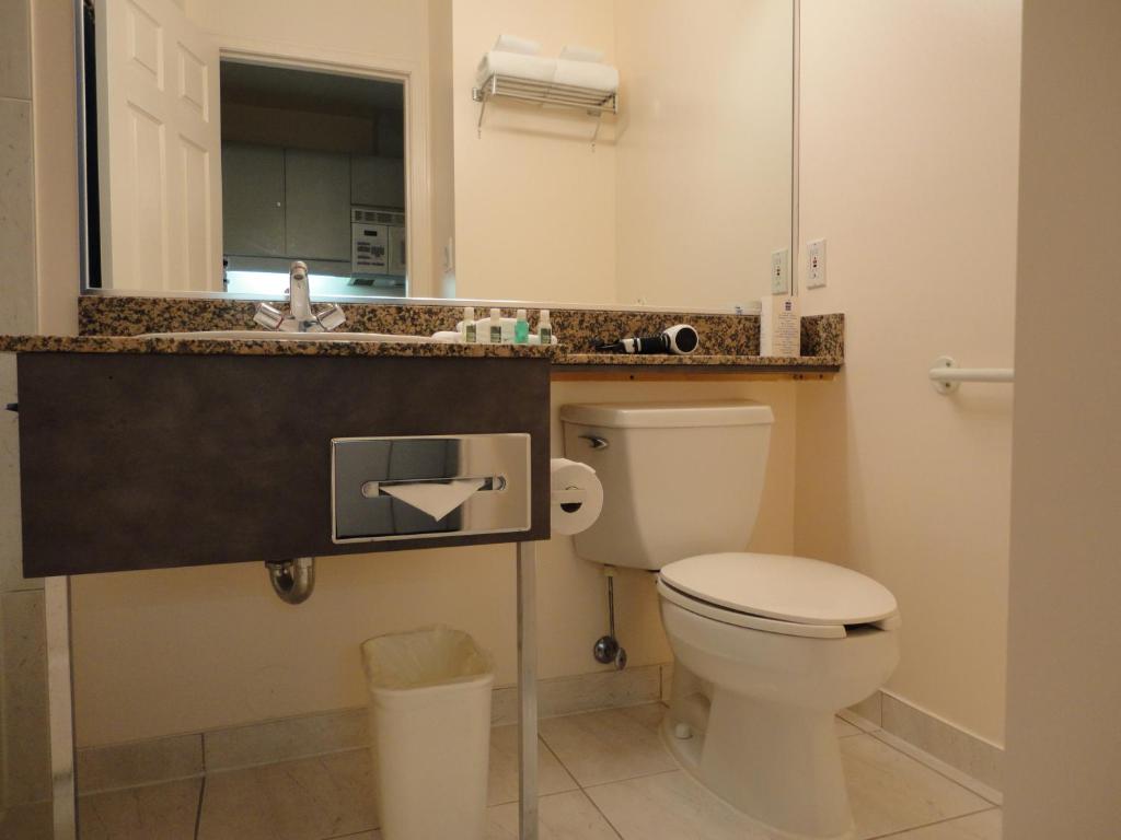 a bathroom with a toilet and a sink and a mirror at Rosedale on Robson Suite Hotel in Vancouver