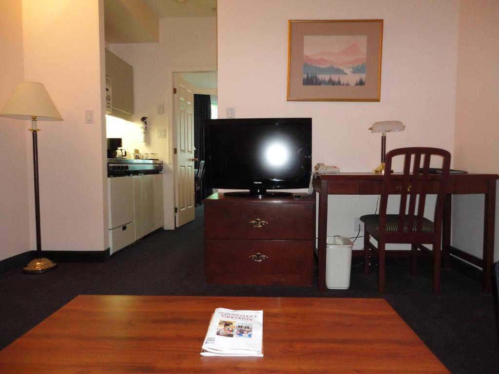 a living room with a tv and a table and a desk at Rosedale on Robson Suite Hotel in Vancouver