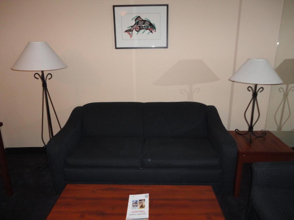 a living room with a black couch and two lamps at Rosedale on Robson Suite Hotel in Vancouver