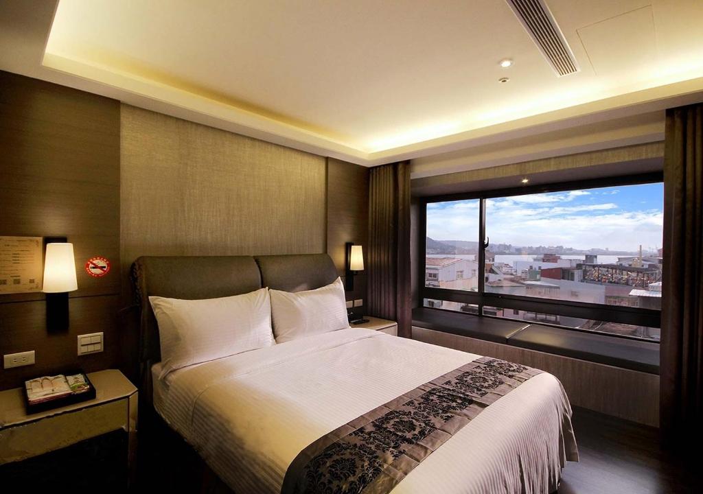 um quarto com uma cama grande e uma janela grande em Open Room Hotel em Tamsui