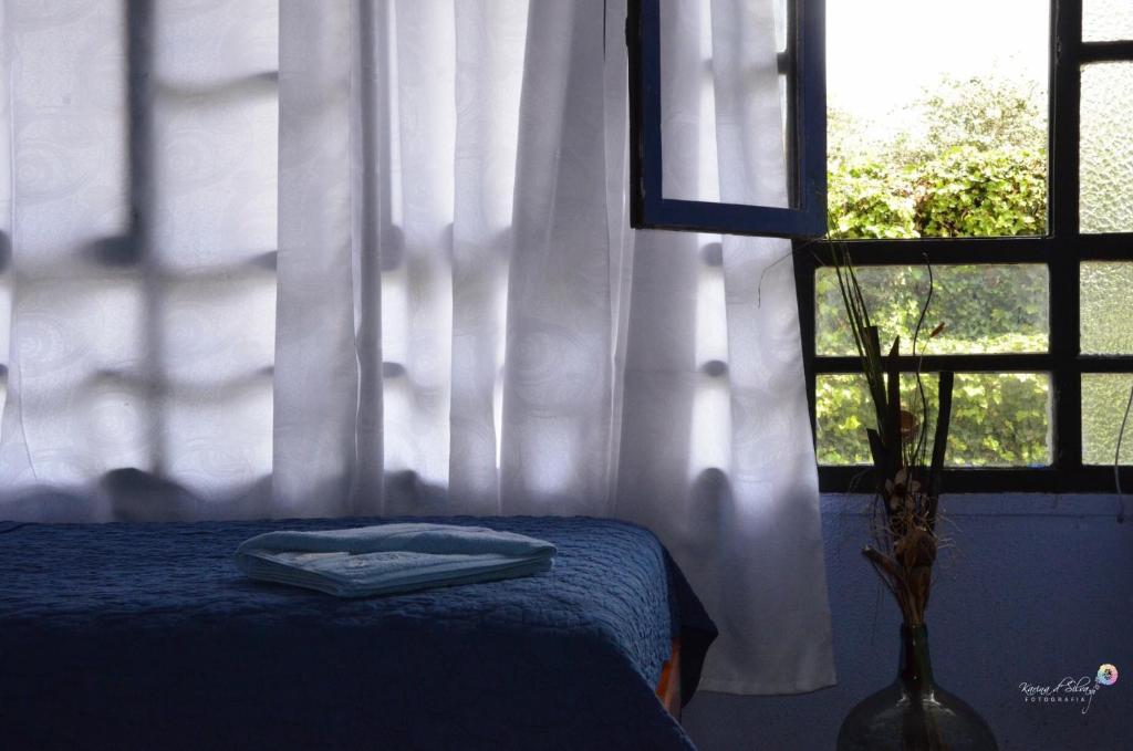 a bedroom with a bed and a window with curtains at Hostal Alua Rio in Quito