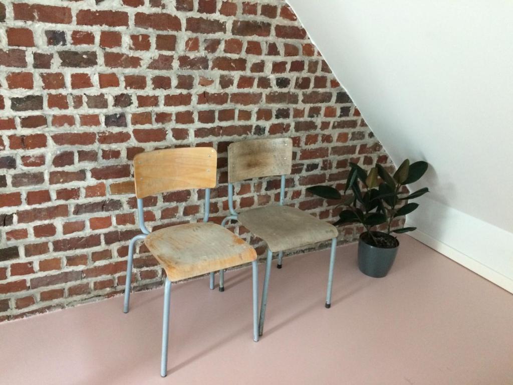two chairs sitting in front of a brick wall at Nelly in Ypres