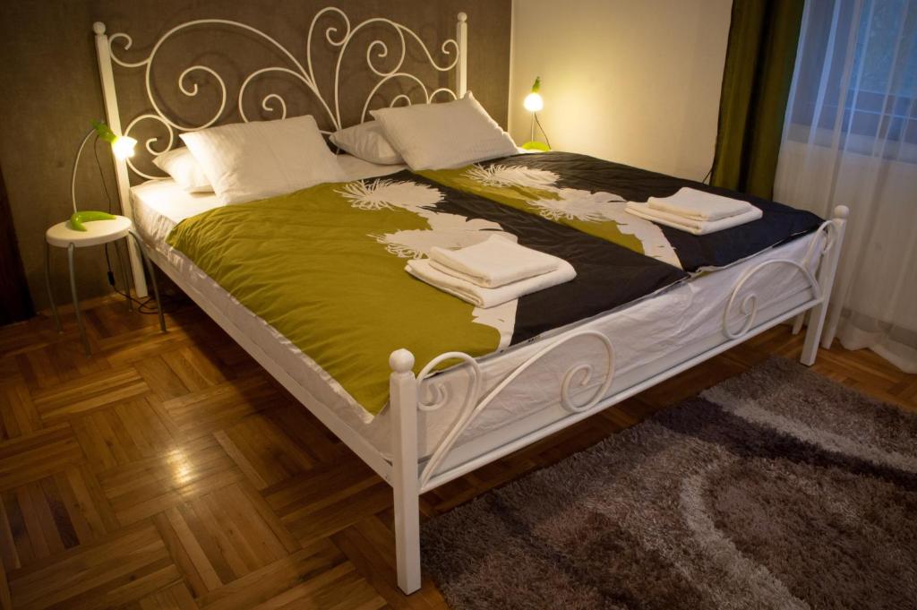 a bed with a white frame and a green blanket at Guest House Ozon in Soko Banja