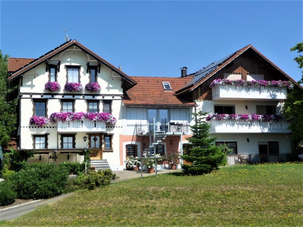une maison blanche avec des fleurs sur les balcons dans l'établissement Gästehaus Reischmann, à Unterreitnau