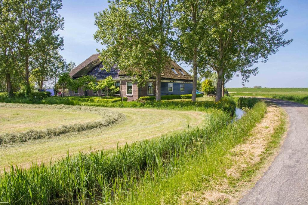 a house in the middle of a field with a dirt road at Traphoeve in Schagen