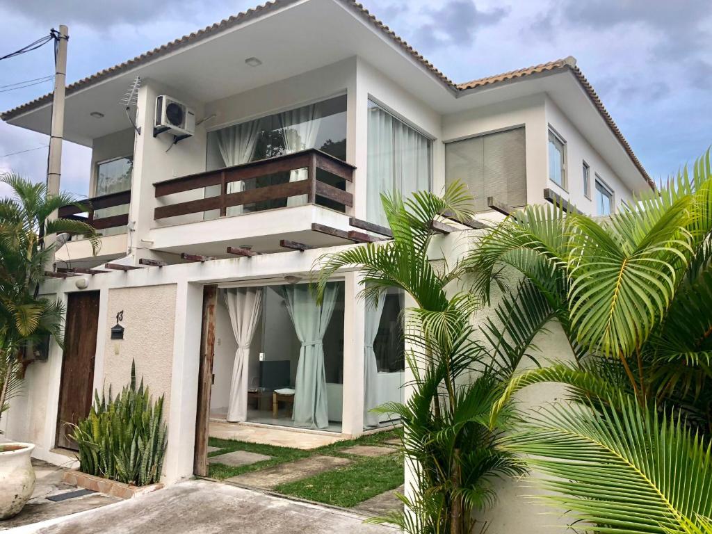 a white house with palm trees in front of it at Villa Vitoria in Cabo Frio