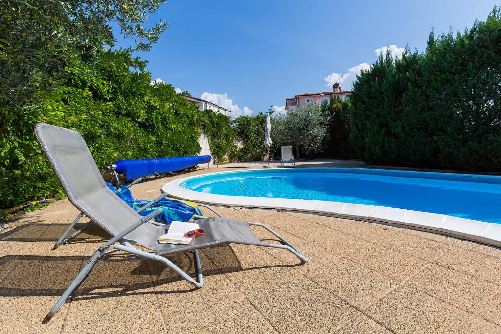 a chair sitting next to a swimming pool at Apartments Radojka in Novigrad Istria