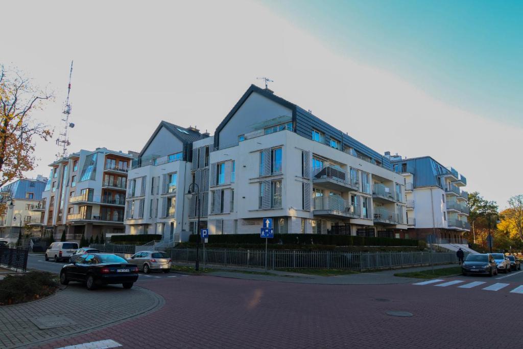 un gran edificio blanco en una calle de la ciudad con coches en Apartamenty Świnoujście - Casa Marina, en Świnoujście