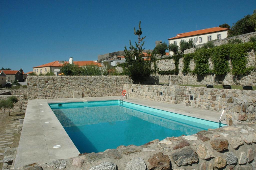 uma piscina em frente a um muro de pedra em INATEL Linhares da Beira Hotel Rural em Linhares