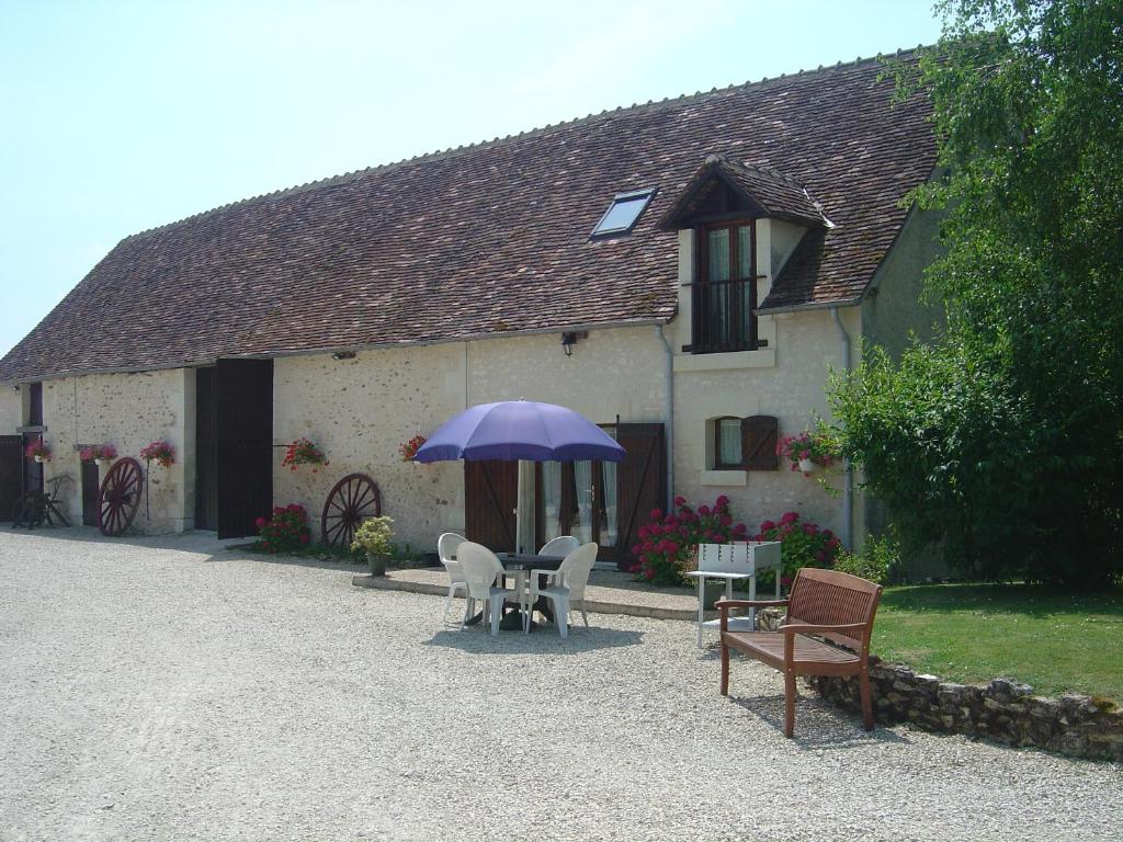 une table avec un parapluie violet devant un bâtiment dans l'établissement Le Cormier, à Obterre