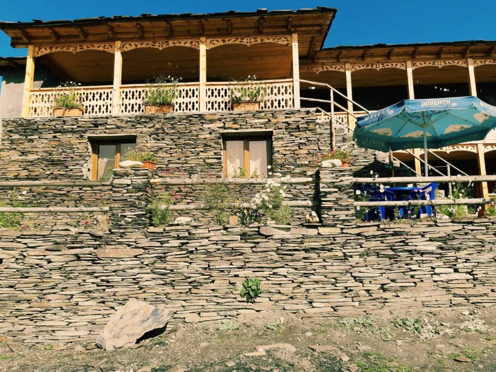a stone building with a table and an umbrella at Guesthouse Lasharai in Omalo