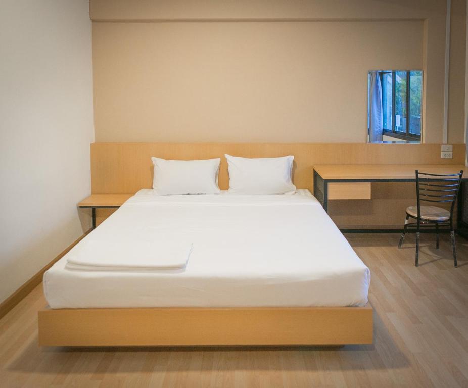 a large bed in a room with a desk and a bed sidx sidx at Grand Leo Hotel in Khon Kaen