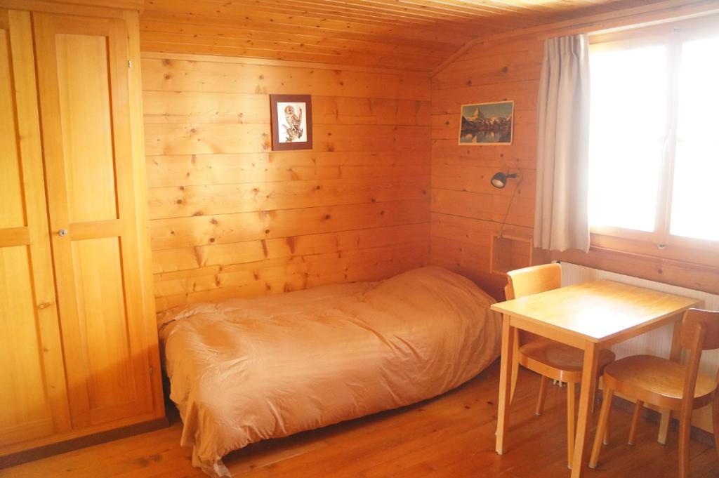 a small bedroom with a bed and a table at Chalet Berken in Ernen
