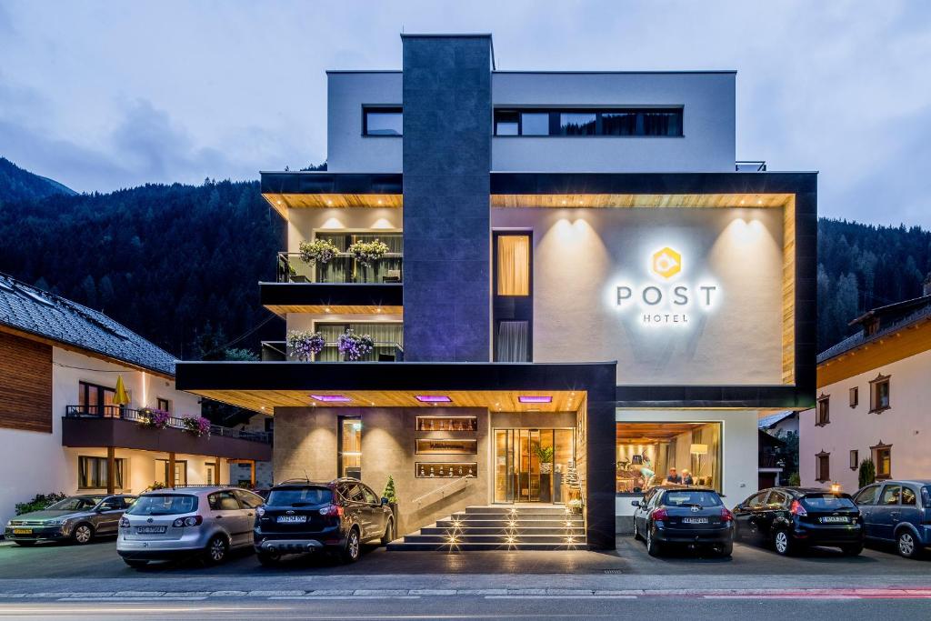 un edificio con coches estacionados en un estacionamiento en Post Hotel Paznaun, en See