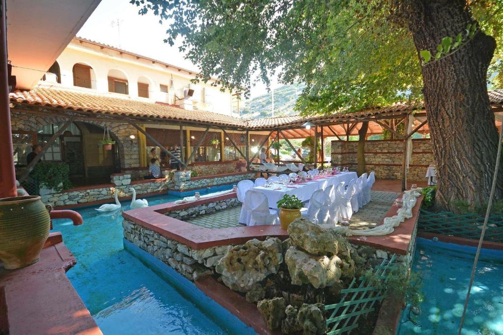 un restaurante con mesa y sillas en una piscina en Lydia Hotel, en Krinídhes