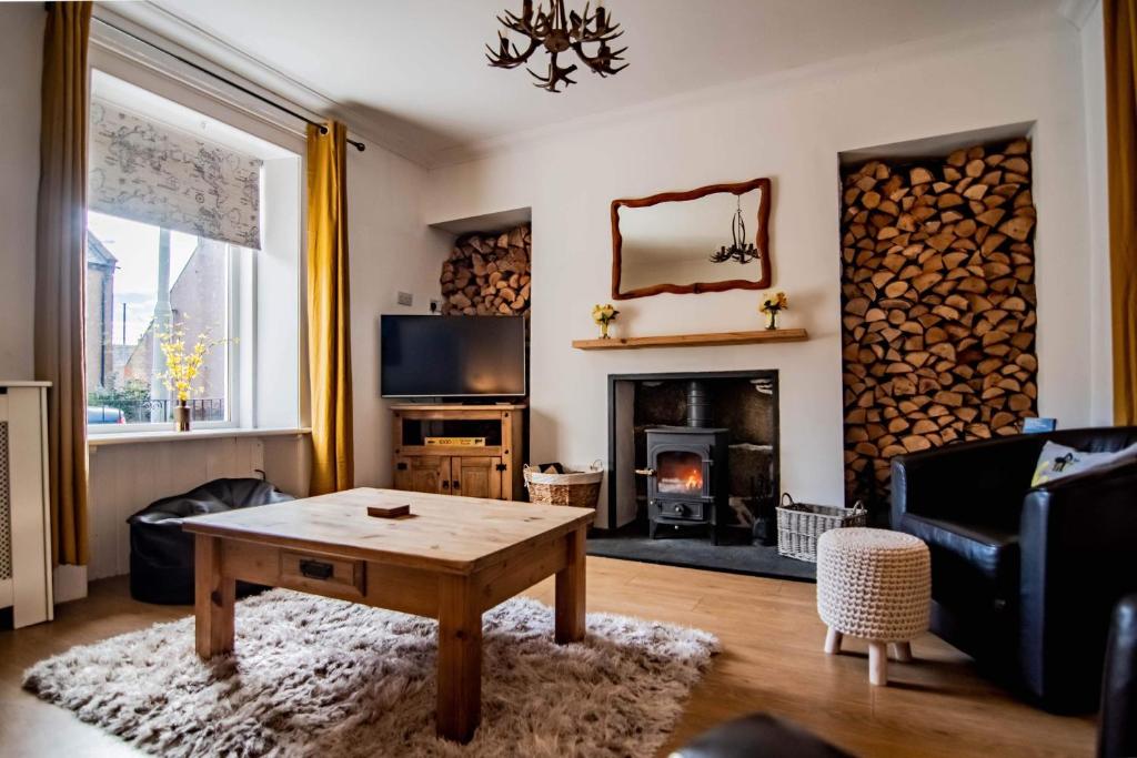 a living room with a table and a fireplace at Wells Street Cottages No 26 By The River Ness in Inverness