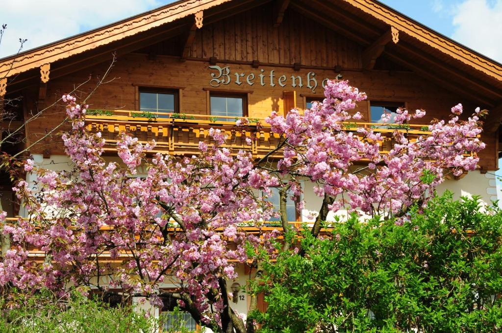 ein Haus mit einem Baum mit rosa Blumen davor in der Unterkunft Breitenhof - Haus Breiten in Angath