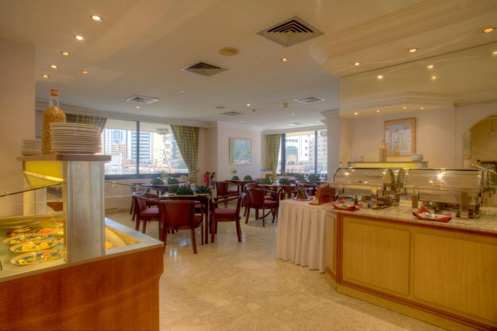 a restaurant with a cafeteria with tables and chairs at Al Diar Mina Hotel in Abu Dhabi