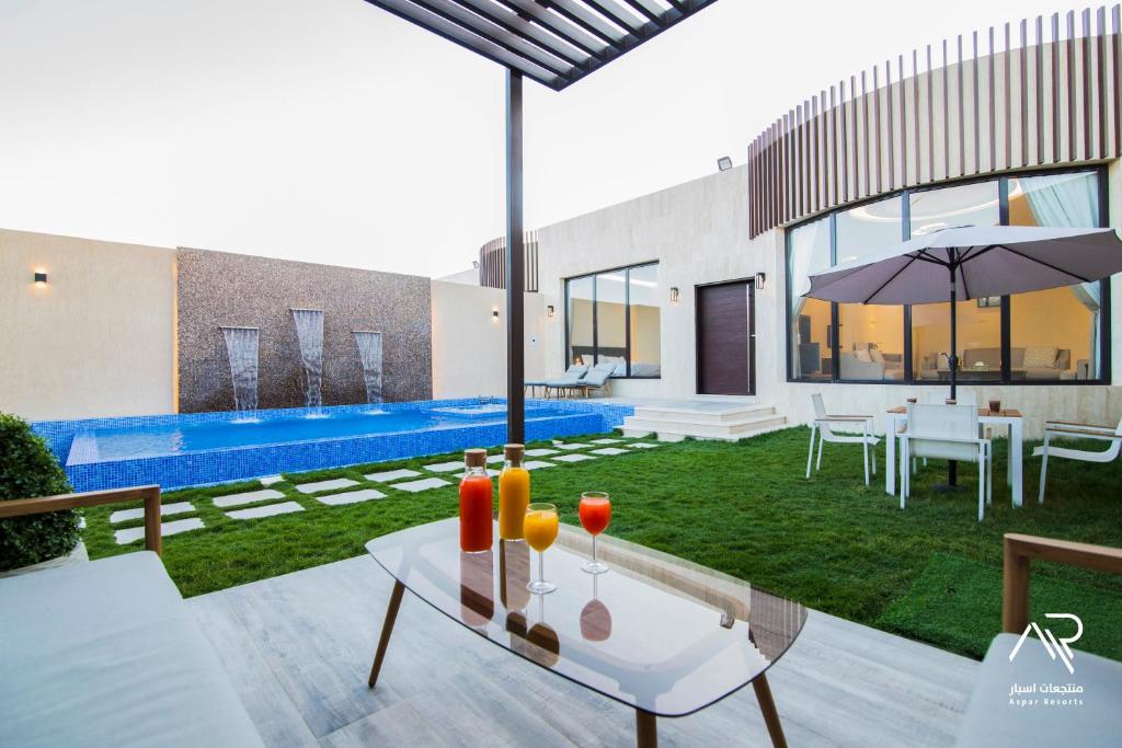 ein Haus mit einem Pool und einem Tisch mit Getränken darauf in der Unterkunft Aspar Resorts in Riad