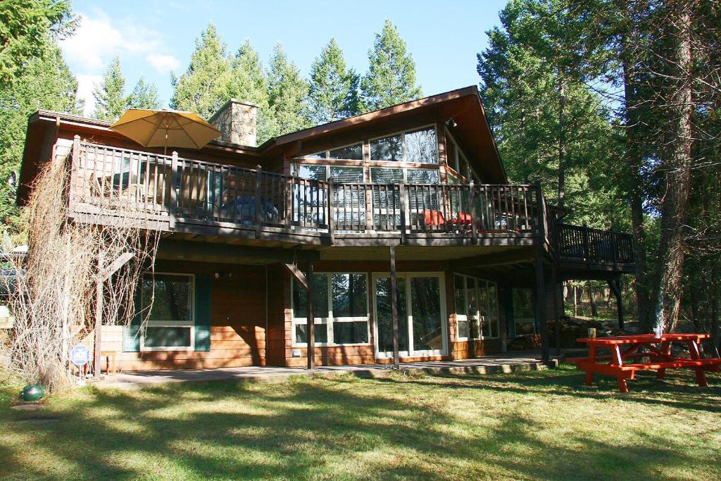 a large wooden house with a deck and an umbrella at Falcon Cabin in Fairmont Hot Springs