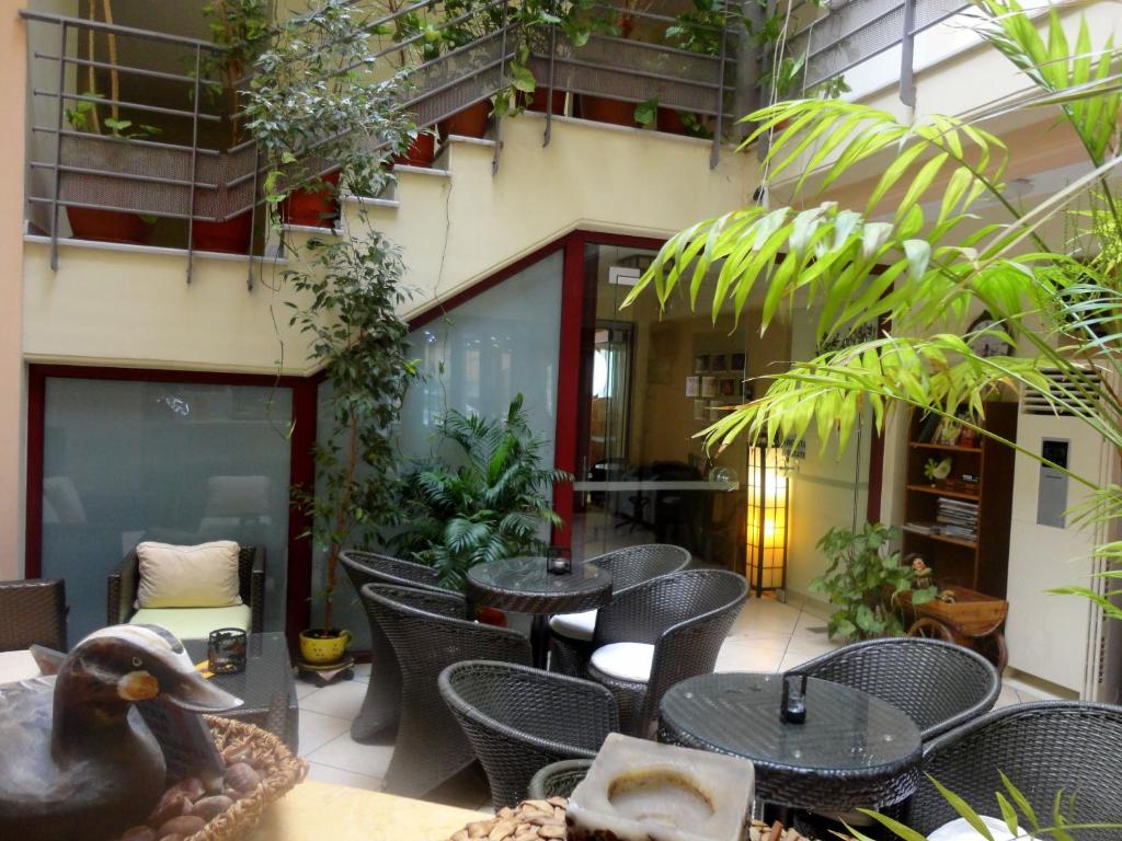 patio ze stołami, krzesłami i roślinami w obiekcie Lirio Guest House w mieście Makrakómi